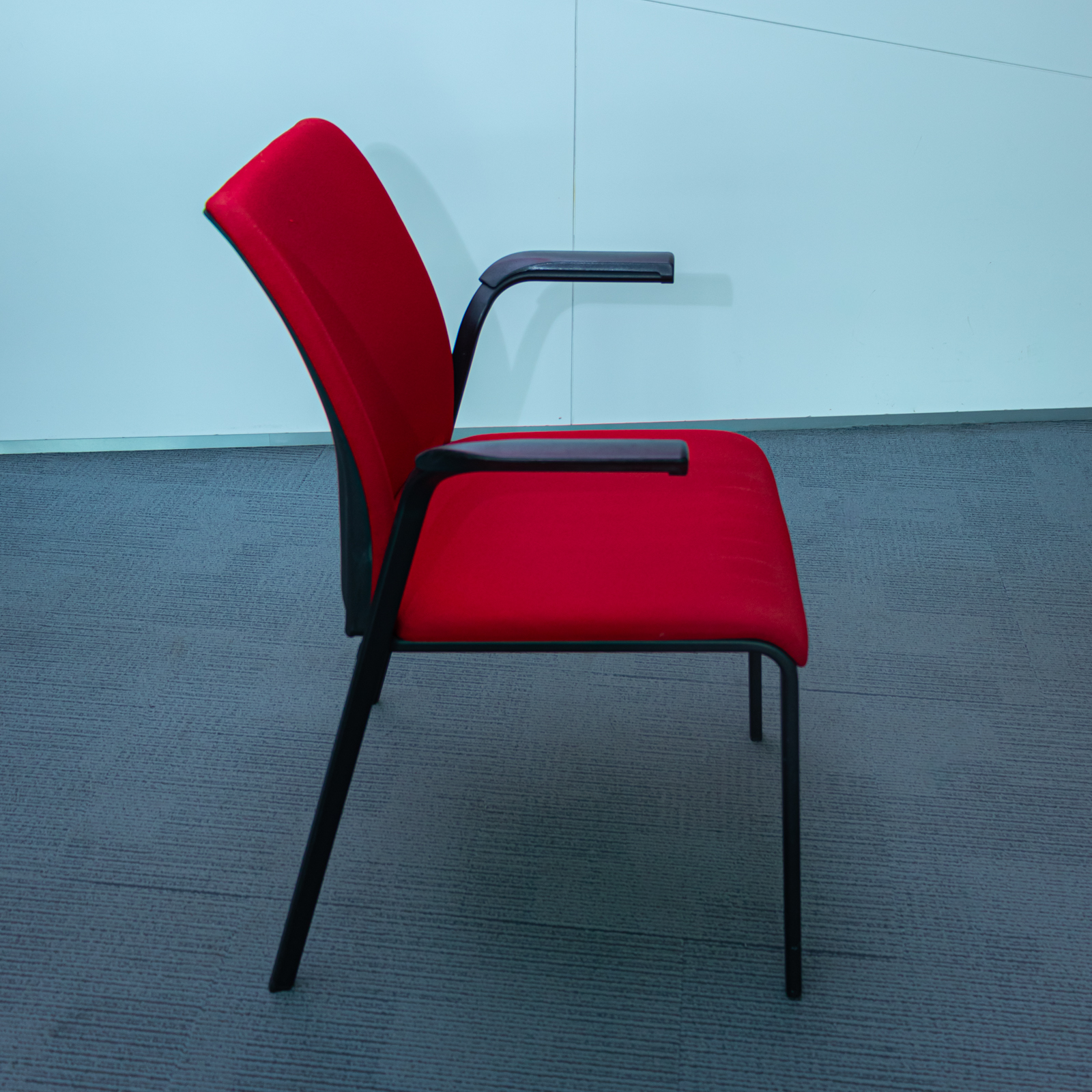 Silla tapizada roja con brazos y estructura metálica negra