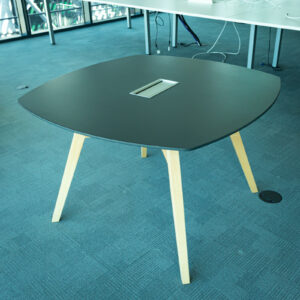 Mesa cuadrada negra con patas de madera y acceso para cableado
