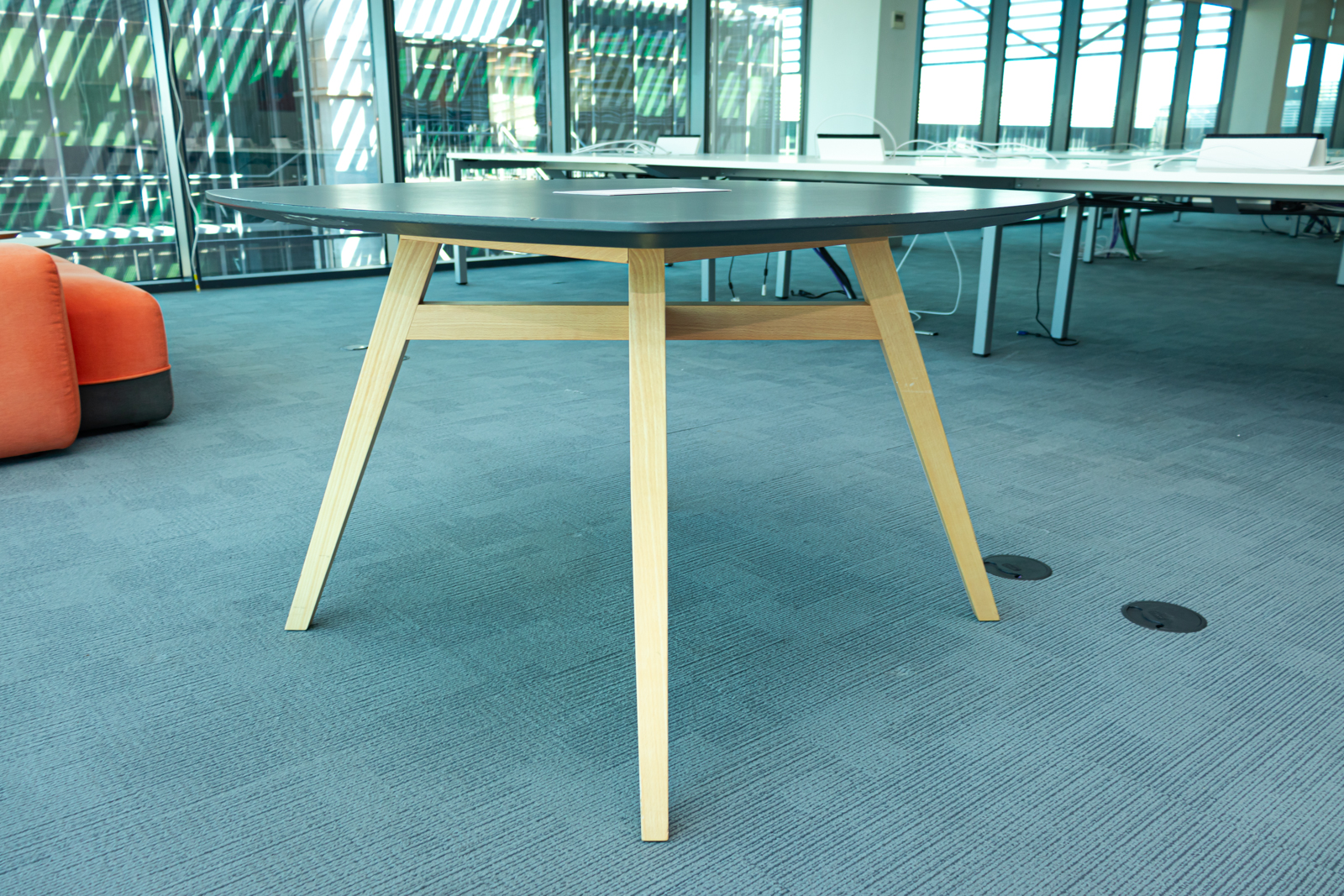 Mesa cuadrada negra con patas de madera y acceso para cableado