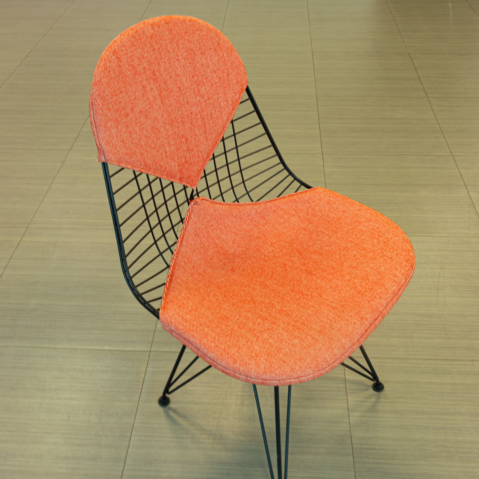 Silla salmón con base de varilla negra y cojines tapizados
