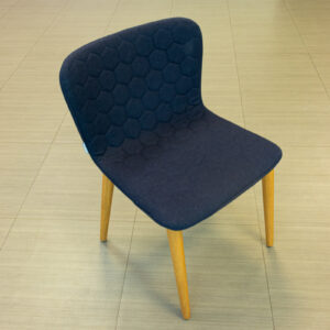 Silla tapizada azul con respaldo acolchado y patas de madera
